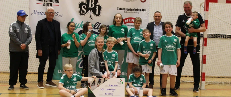 På billedet ses spillere fra SBI LykkeLiga, trænerne Katrine Olsen og Jacob Olsen, filialdirektør i Sparekassen Sjælland-Fyn, Klaus Koksby Hansen, og bestyrelsesmedlem i Sparekassen Sjælland Fonden, Kjeld Christensen.