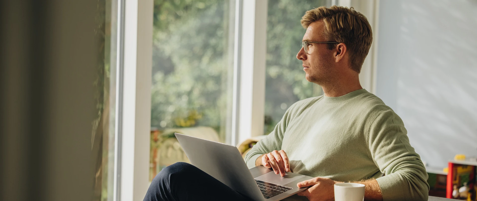 Mand sidder med PC og kigger ud af vindue