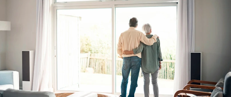 Par står og kigger ud af vinduet i deres hus